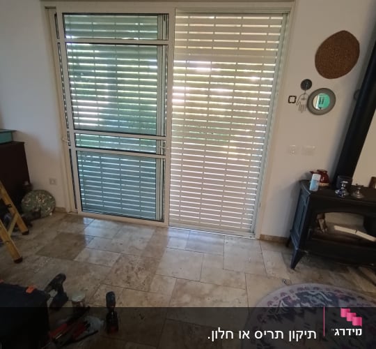 תריסים לבנים מותקנים על חלון גדול בחדר פנימי